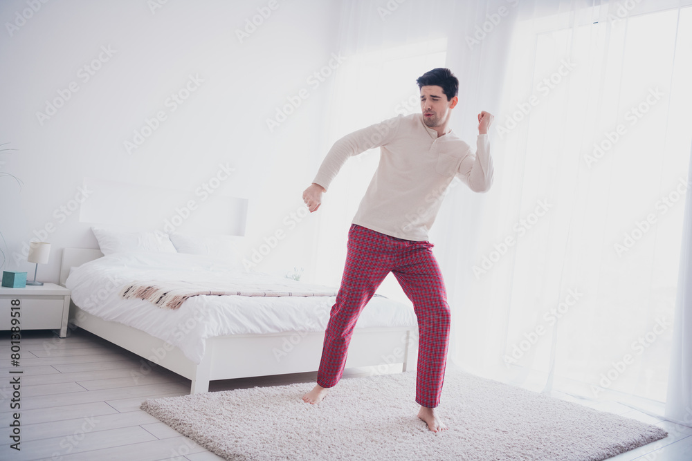 Photo of cheerful positive carefree man wearing trendy pajama dancing alone in bedroom indoors Photo of cheerful positive carefree man wearing trendy pajama dancing alone in bedroom indoors