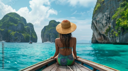 Woman in straw hat enjoying a scenic boat ride by limestone cliffs and turquoise waters.