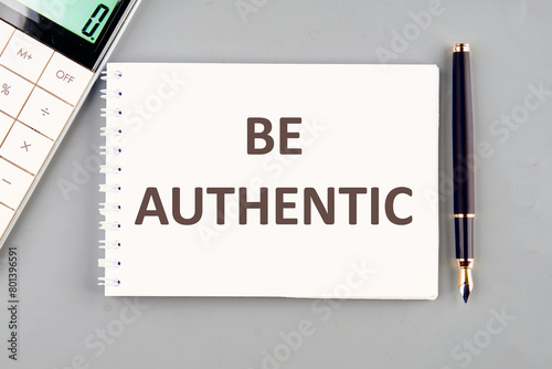 Be Authentic written on a white notebook on a gray background