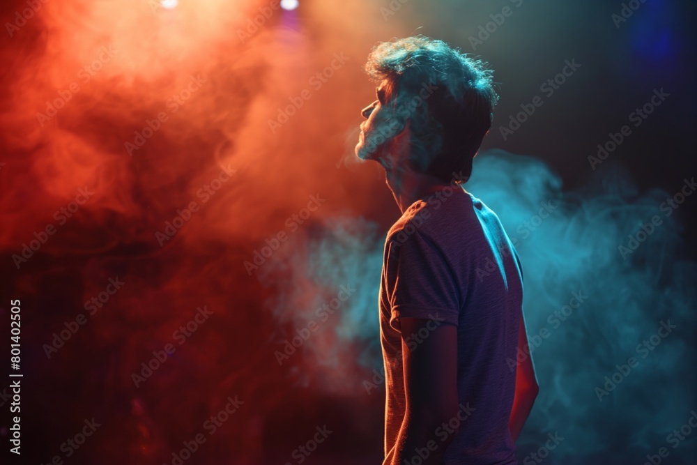 A young person on a stage with vibrant smoke, multicolored lights