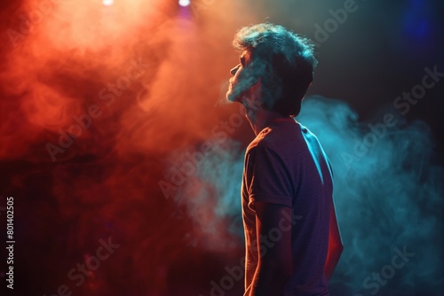 A young person on a stage with vibrant smoke, multicolored lights