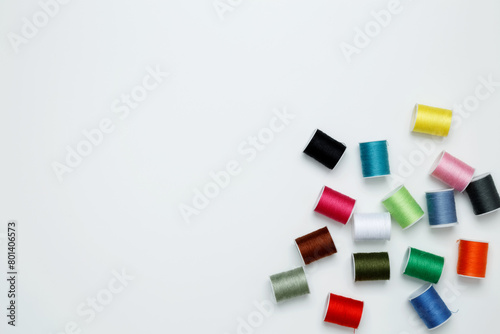 Multicolored sewing threads on white background. Top view, copy space
