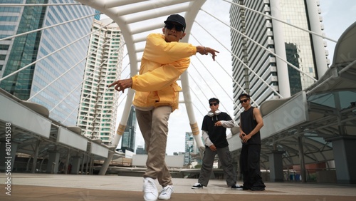 Group of professional street dancer cheer up while asian hipster perform freestyle footstep at city surrounded by people with low angle camera. Break dance concept. Outdoor sport 2024. Sprightly. photo