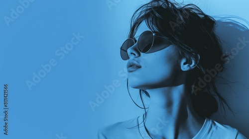 Stylish woman in sunglasses with windblown hair against a blue background. photo