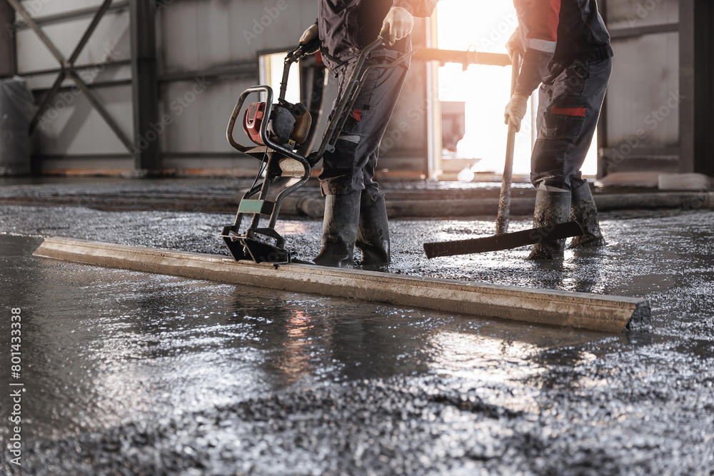 Team Workers uses vibrating machine to level cement mortar for floors. Concrete screed for buildings, construction site Team Workers uses vibrating machine to level cement mortar for floors. Concrete screed for buildings, construction site