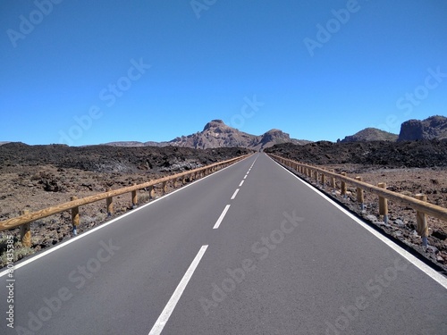 Driving along the road along Teide POV shot from a camera driving through beautiful empty road. Concept of transport and driving point of view. Mountain travel journey. Trees and sky in nature