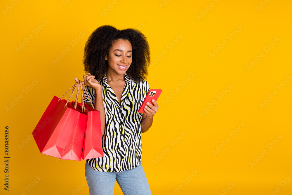 Photo of glamour woman using cellphone surfing internet with shopping bags curly hair in zebra print shirt isolated on yellow color background Photo of glamour woman using cellphone surfing internet with shopping bags curly hair in zebra print shirt isolated on yellow color background