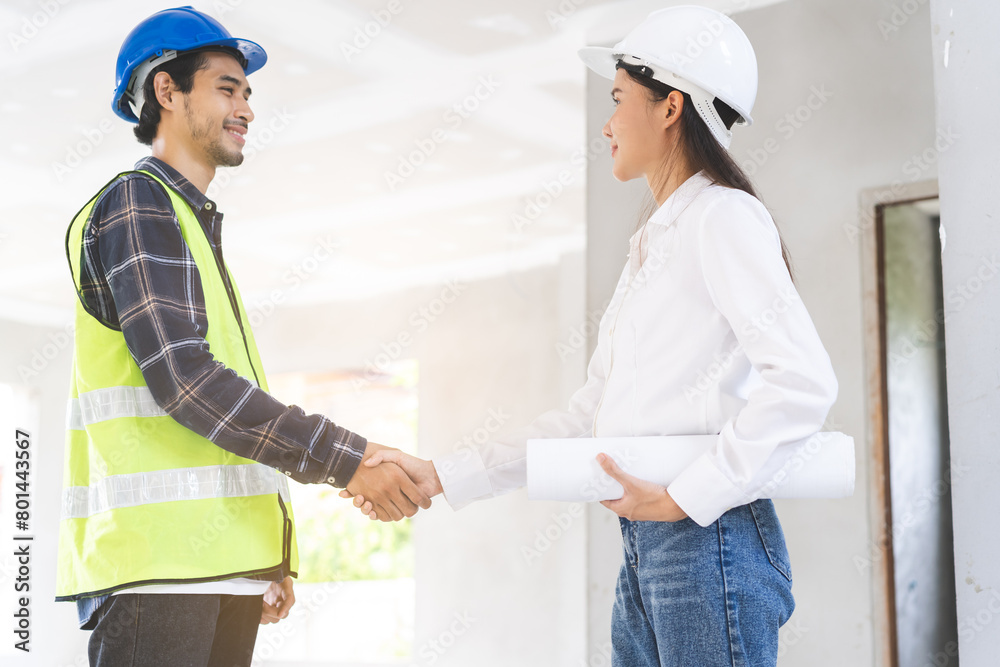 Obraz premium Engineer team building, teamwork contractor, two asian young partnership, builder agreement handshake plan home project contract at construction site .Happy architect, surveyor worker shaking hand.