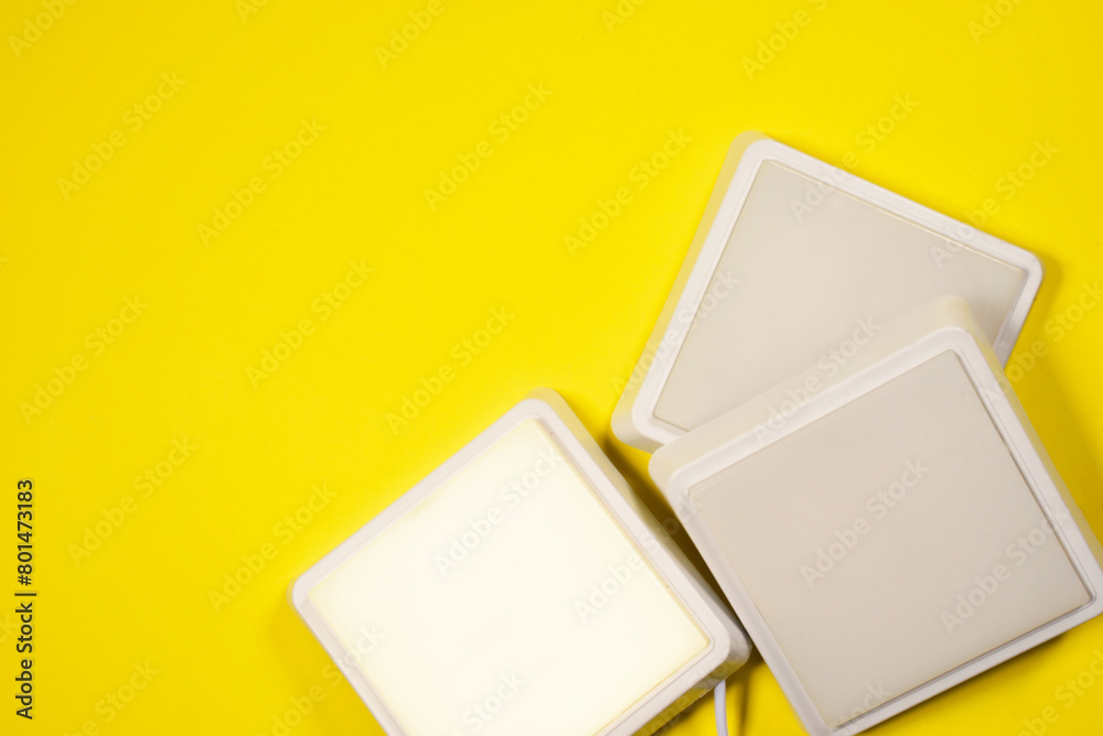 White led square led lamps on the yellow flat lay background with copy space.