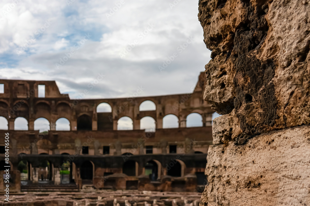 Selective focus on wall with blurred view on interior of famous Colosseum of city Rome, Lazio, Italy, Europe. UNESCO World Heritage Site. Flavian Amphitheater the symbol of ancient Roma, Roman Empire