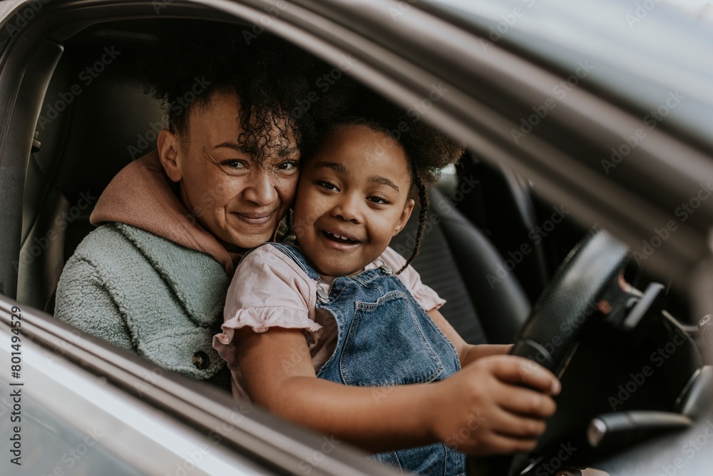 Daughter sitting on mother's lap in a car Daughter sitting on mother's lap in a car