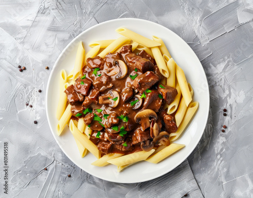 Pasta with beef stroganoff and mushrooms on a gray background
