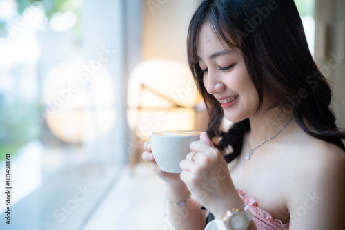 Portrait of beautiful happy Smiling Holding a glass of Hot coffee latte asian woman relaxing sitting in cafe interior in coffee shop background,Business Lifestyle summer holiday concept