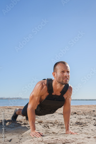 young man does exercises on the beach outdoors (ID: 801502775)