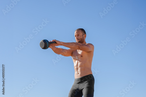 young man does exercises on the beach outdoors