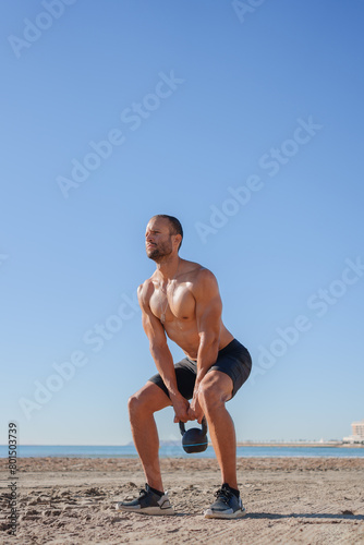 young man does exercises on the beach outdoors (ID: 801503739)