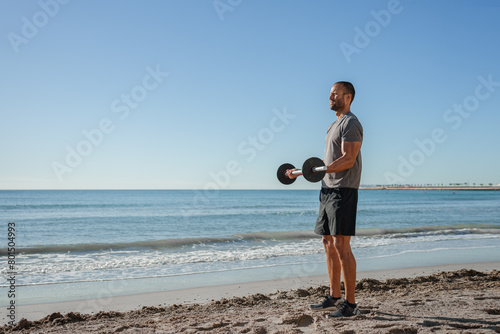 young man does exercises on the beach outdoors (ID: 801504993)