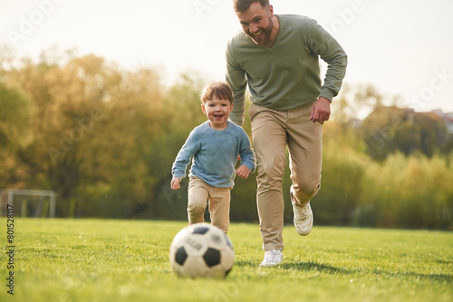Learning to play soccer. Happy father with son are having fun on the field at summertime © standret
