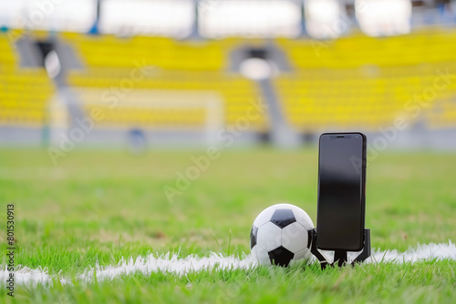 Mobile phone with soccer ball on green grass in stadium. 5G football concept