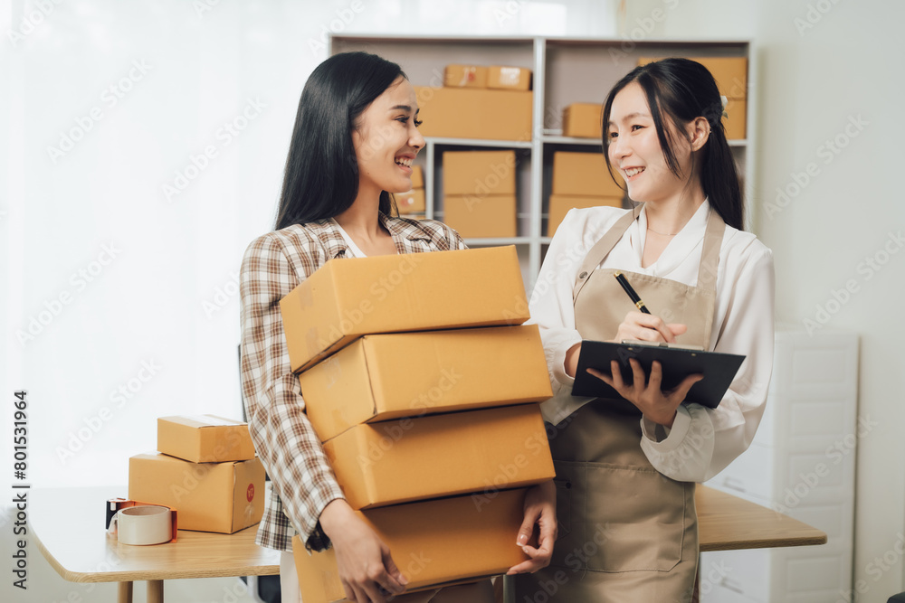 Asian businesswoman using laptop computer checking customer's shipping box online at home. SME startup. Small business entrepreneur, freelancer. Online business, SME work
