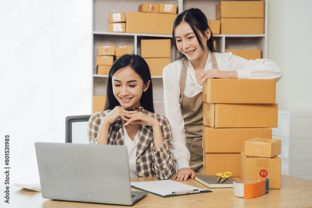 Asian businesswoman using laptop computer checking customer's shipping box online at home. SME startup. Small business entrepreneur, freelancer. Online business, SME work Asian businesswoman using laptop computer checking customer's shipping box online at home. SME startup. Small business entrepreneur, freelancer. Online business, SME work