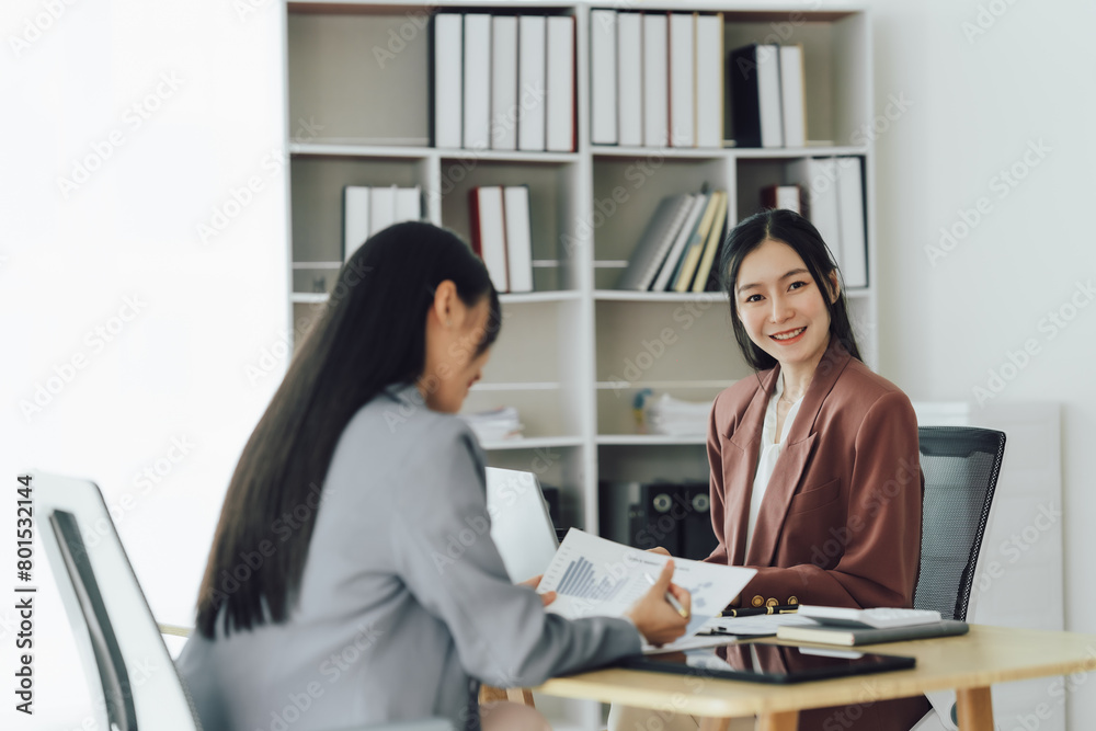 Two young Asian business woman talk, consult, discuss working with new startup project idea presentation analyze plan marketing and investment in the office. Two young Asian business woman talk, consult, discuss working with new startup project idea presentation analyze plan marketing and investment in the office.