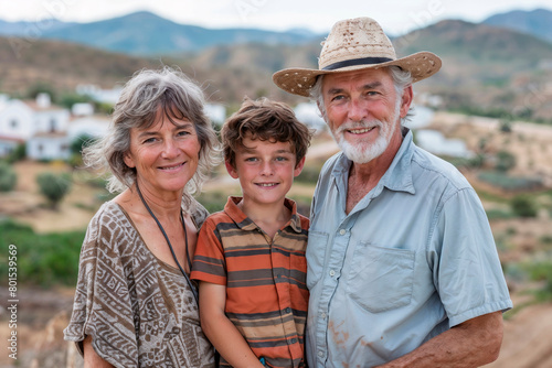 Portrait of grandparents with their grandson in a rural area overlooking a Mediterranean village with white houses
