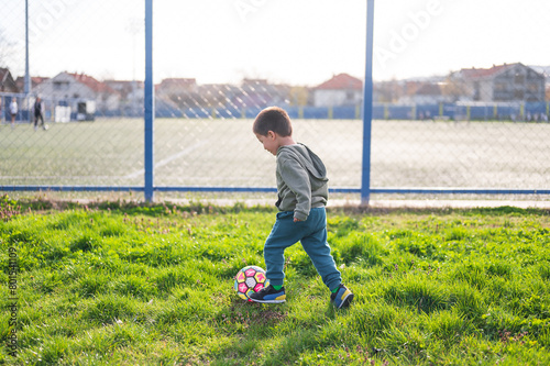 Little boy playing with soccer ball on the grass