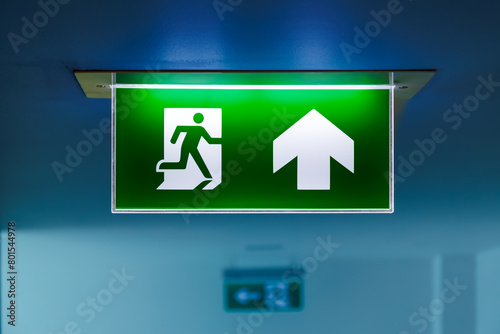 close-up green fire emergency exit sign on the ceiling showing the way to escape  © nutt