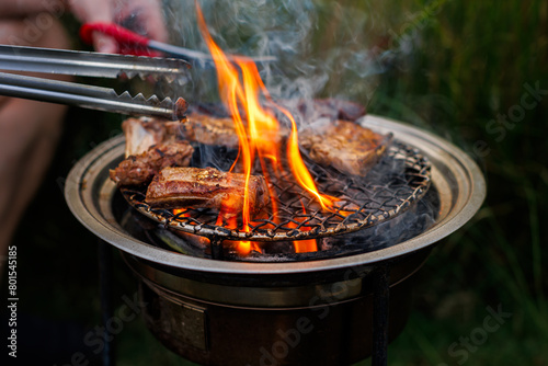skewers meat ribs and sausage barbecue grilled on the grill with charcoal flames in camping party outdoor