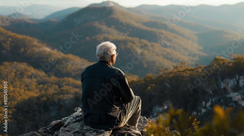 Elderly man enjoying a scenic view from a mountain lookout photo