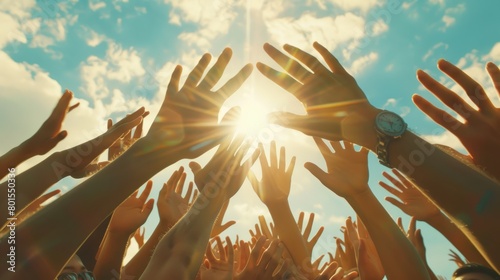 Upward view of hands reaching towards the sun against a blue sky. Unity and togetherness concept.