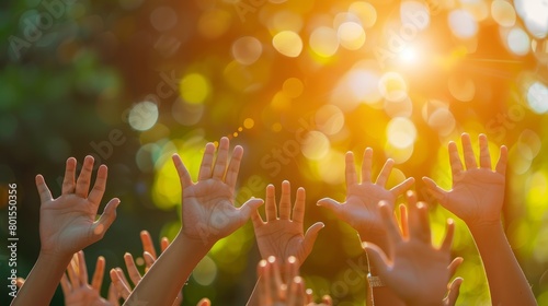 Raised hands of diverse children against sunlit green foliage background. Macro shot with copy space.