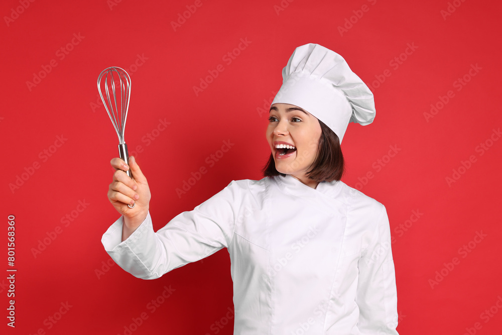 Naklejka premium Happy confectioner holding whisk on red background