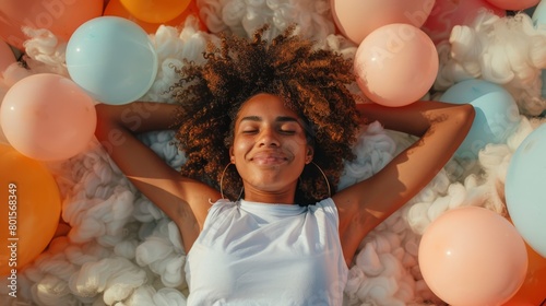   A woman reclines on a bed of balloons, her eyes closed, and her head cradled in her hands behind her head photo