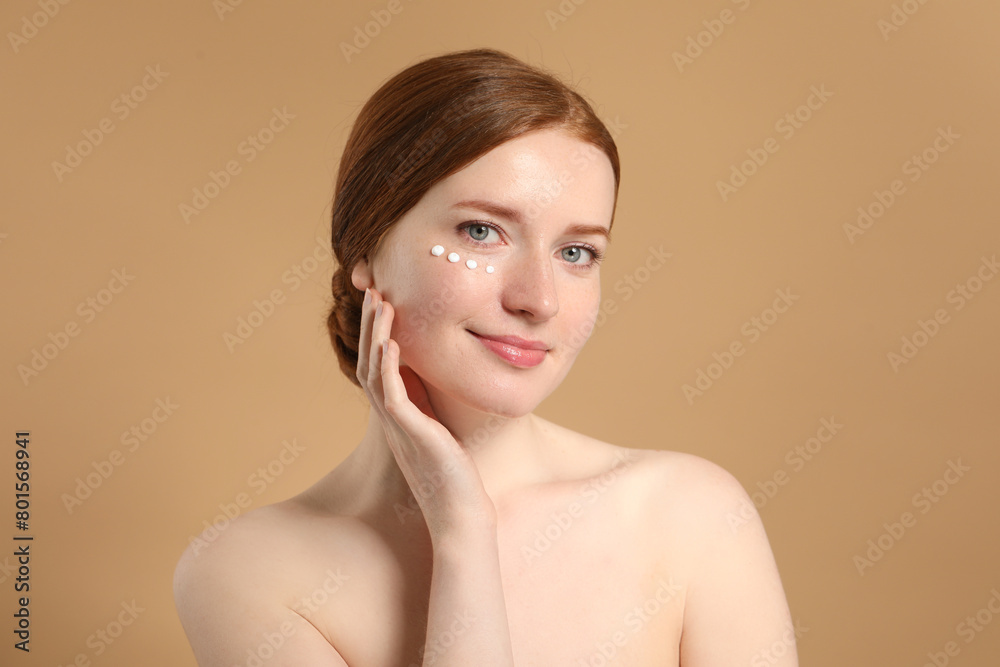 Beautiful woman with freckles and cream on her face against beige background Beautiful woman with freckles and cream on her face against beige background