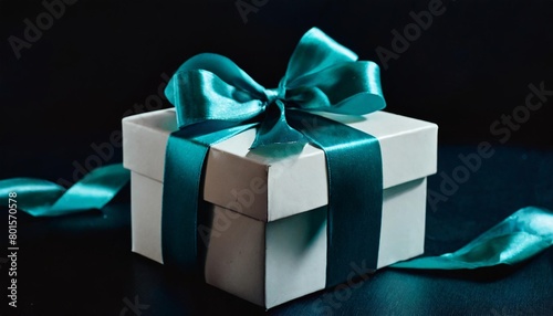 a white gift box with a teal ribbon and a bow on the top of it on a blue background