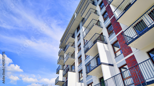 A view at a detail of a modern white apartment building with blue sky background.