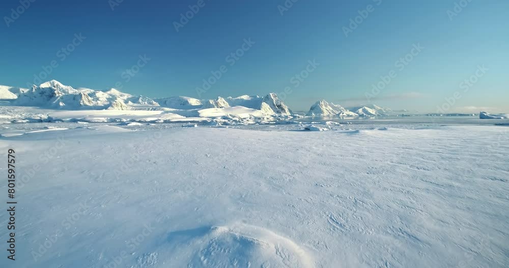 Winer snow covered Antarctica aerial landscape. Frozen ocean and towering mountain range under blue clear sky, sunny wild nature scene. Sea polar coast hill. Antarctic travel exploration background