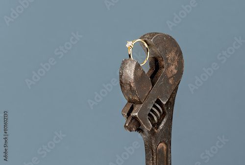 Jewelry workshop concept made with old worn-out crescent wrench and elegant elegant gold diamond ring.