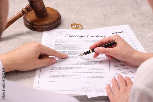 Картината върху платно Man and woman signing marriage contract at light grey table, closeup