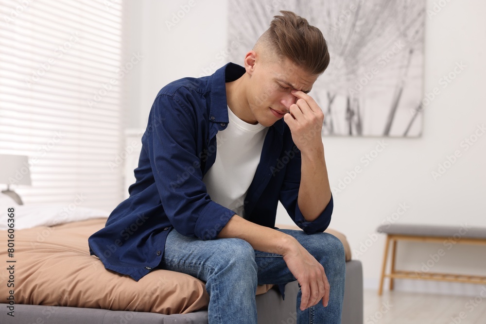 Overwhelmed man sitting on bed at home Overwhelmed man sitting on bed at home