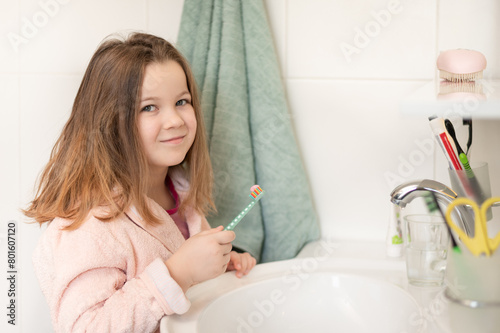 Happy 7 year old child brushes his teeth in the bathroom near the mirror with a toothbrush