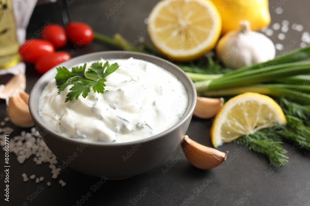 Delicious yogurt in bowl and ingredients on black table, closeup Delicious yogurt in bowl and ingredients on black table, closeup