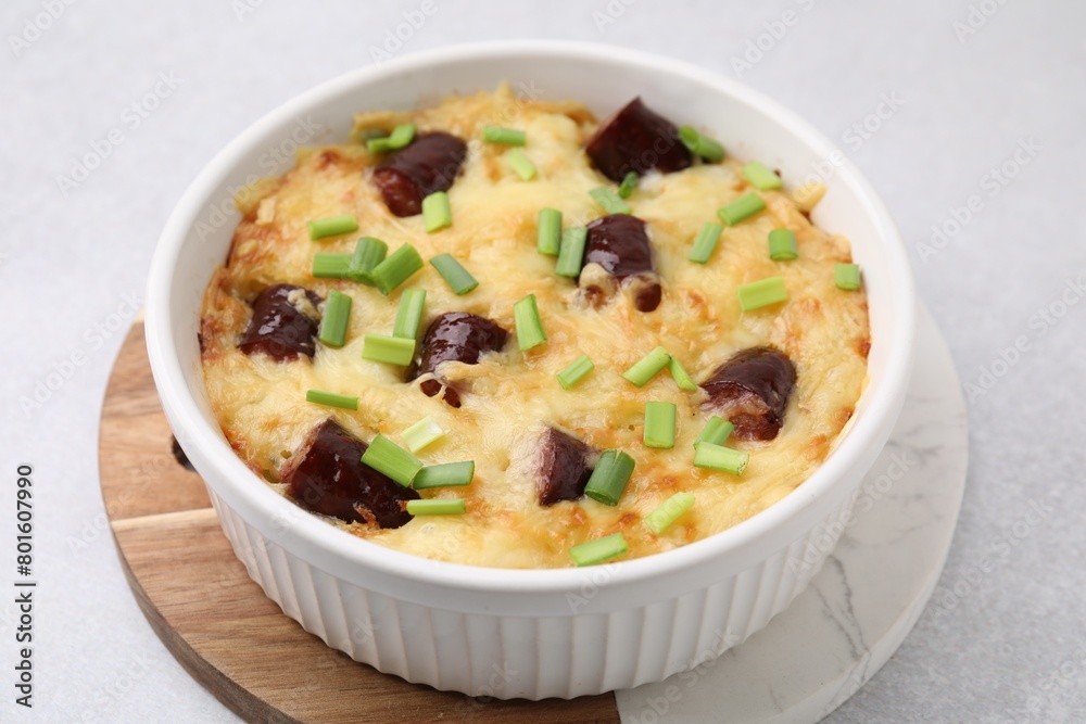 Tasty sausage casserole with green onions in baking dish on white table, closeup Tasty sausage casserole with green onions in baking dish on white table, closeup