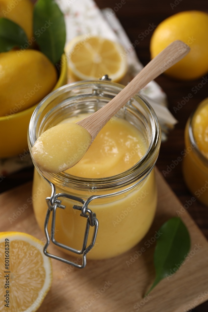 Delicious lemon curd in glass jar, spoon, fresh citrus fruits and green leaves on table Delicious lemon curd in glass jar, spoon, fresh citrus fruits and green leaves on table