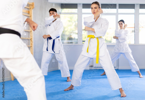 Team of athletic people in kimonos try new fighting techniques at karate lessons
