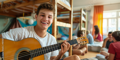 Young tourist sitting on bunk bed and playing a guitar in hostel room. Roommates singing and partying in contemporary youth hostel. photo