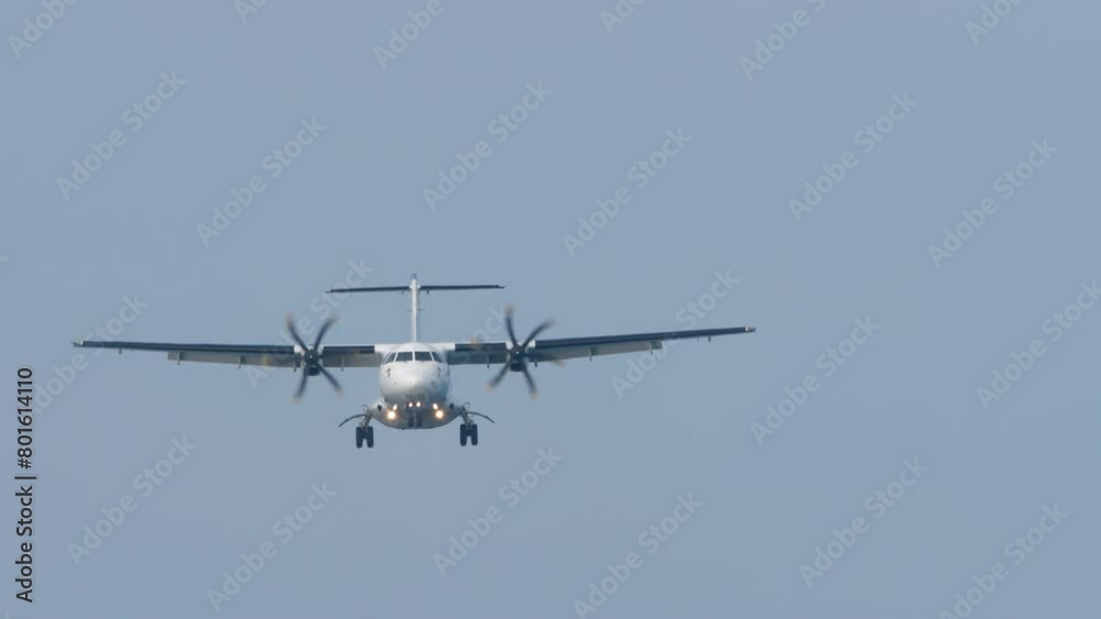 Front view of a turboprop airplane with an unrecognizable livery flying, descending for landing. Twin-engine short-haul regional passenger aircraft. Blue background. Front view of a turboprop airplane with an unrecognizable livery flying, descending for landing. Twin-engine short-haul regional passenger aircraft. Blue background.