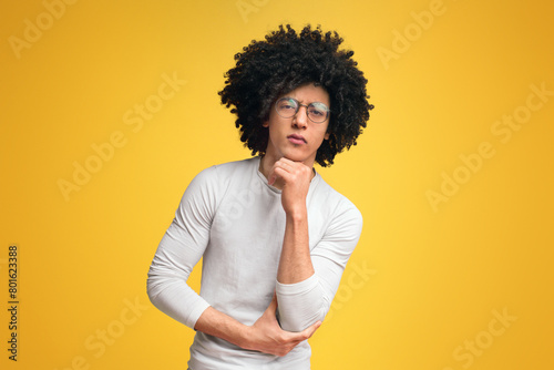 Doubtful black man looking seriously at camera, orange background
